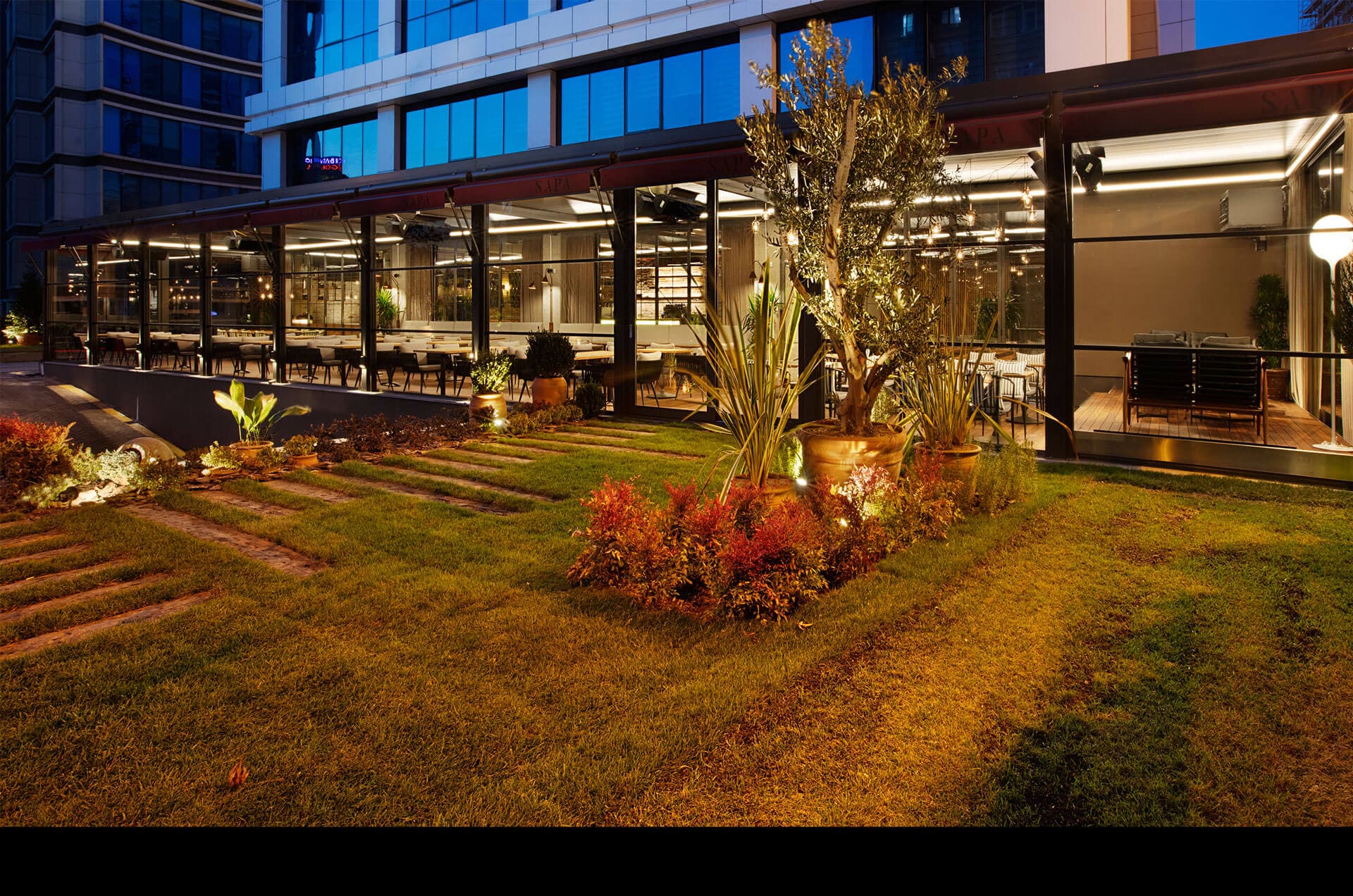 Commercial glass enclosure at night with outdoor dining