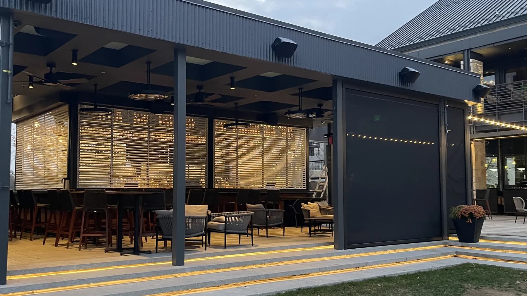 Covered commercial patio with dining seats and lowered screens