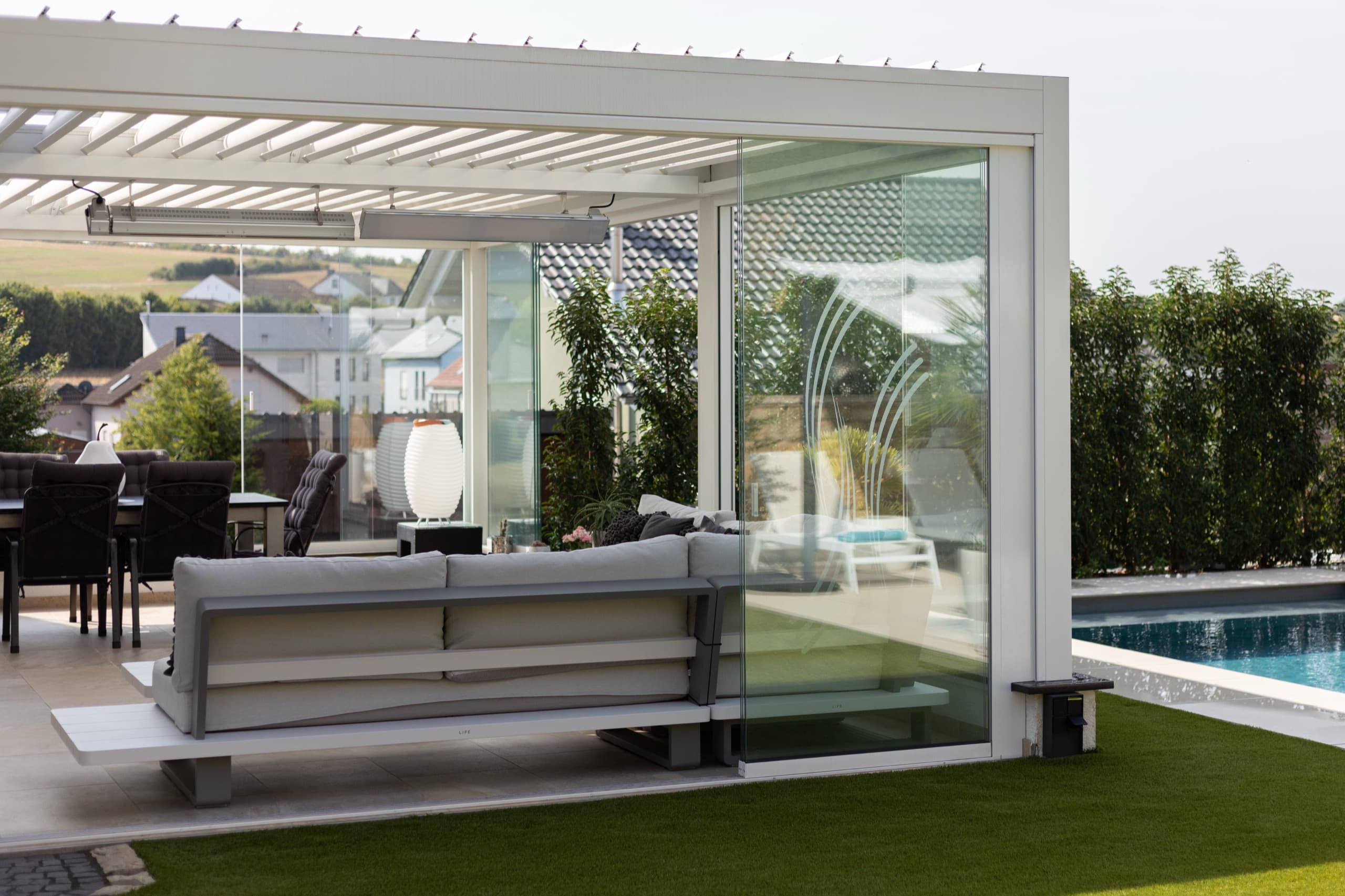 White motorized pergola with glass doors by pool