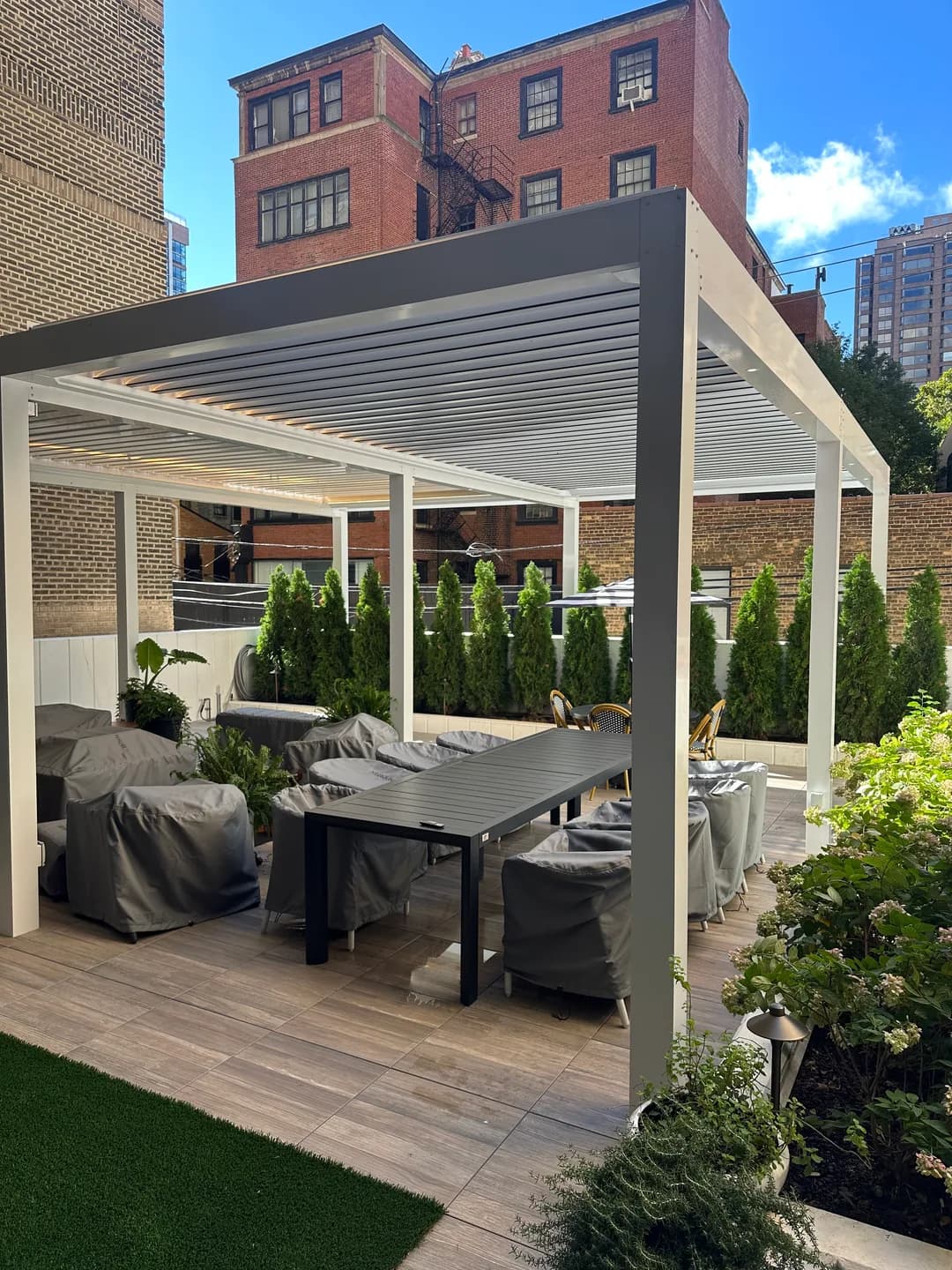 White louvered pergola with gray columns over courtyard patio seating