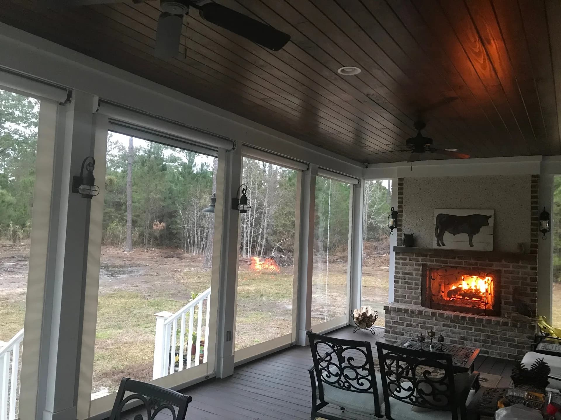 Clear retractable vinyl panels around a covered porch with a brick fireplace
