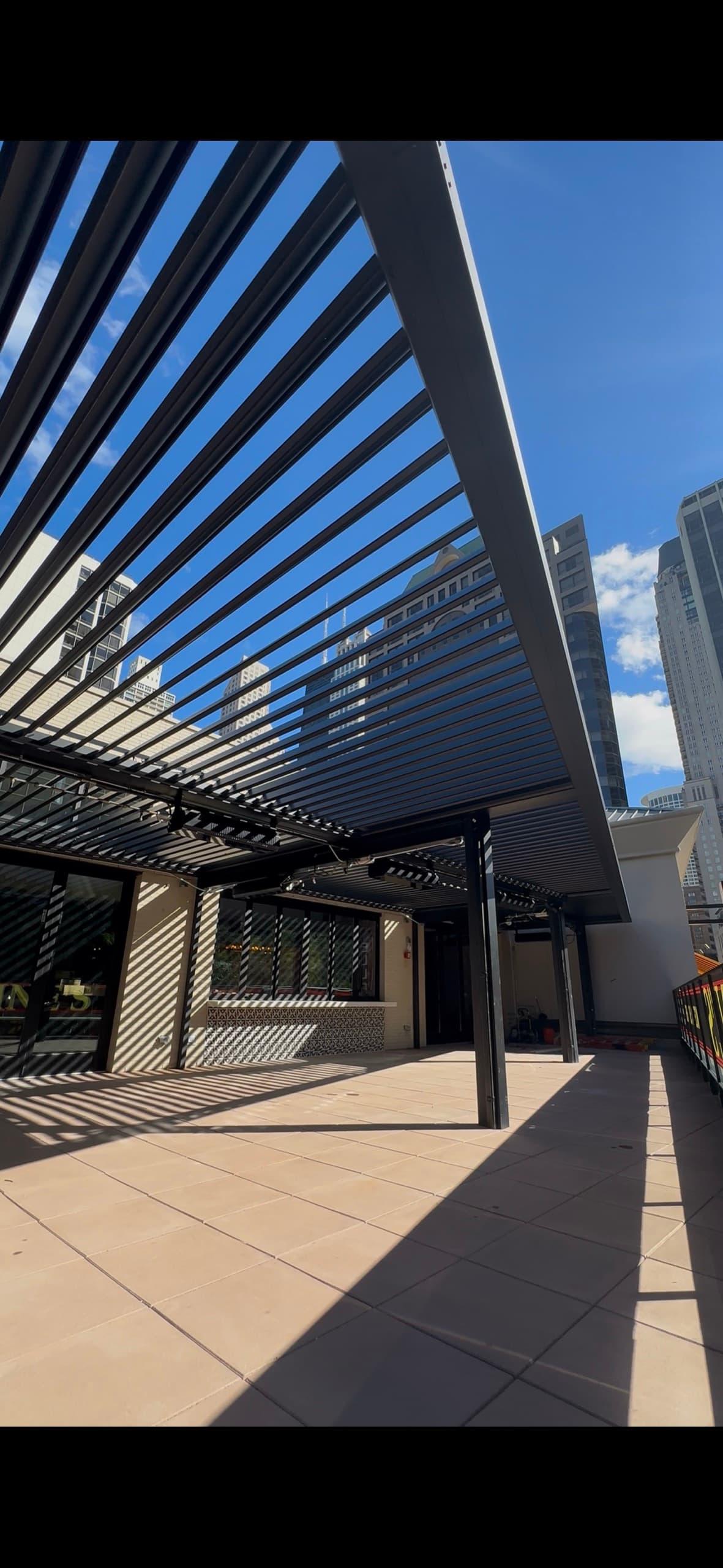 Louvered pergola installation with urban skyline backdrop
